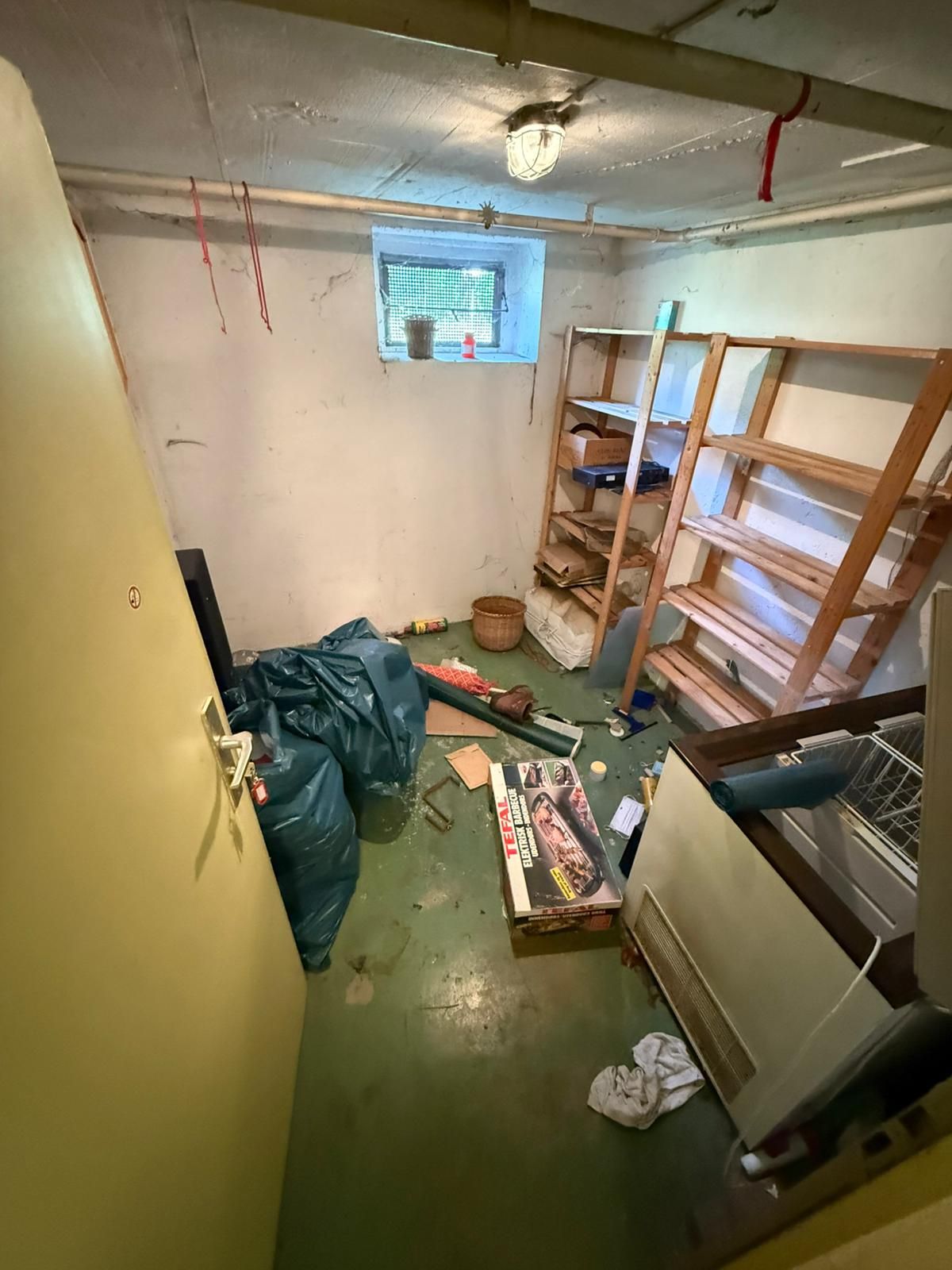 Vorher: Kellerraum in Weinstadt mit Holzregalen, Gefriertruhe, Kartons und blauen Müllsäcken auf dem Boden